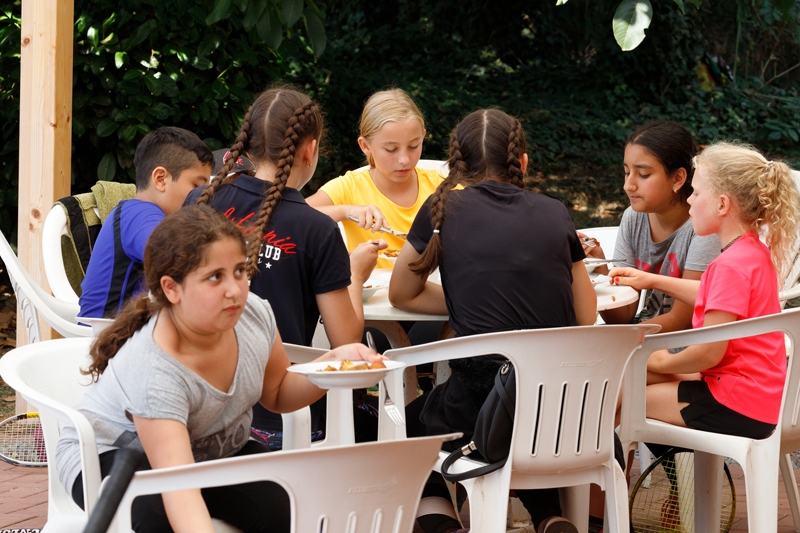 Mehrere Kinder beim Essen an einem weißen Tisch